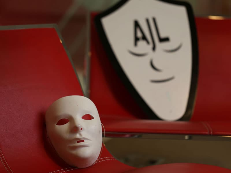 a white mask on a red seat, the AJL logo is in the background